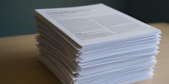 A stack of research papers sits on a desk