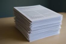A stack of research papers sits on a desk